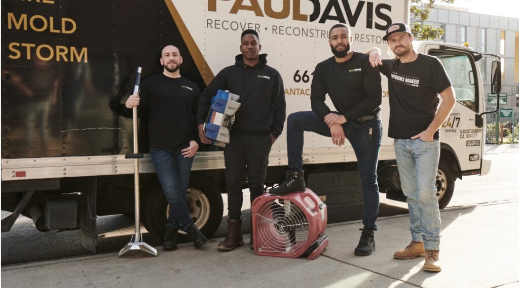 Paul Davis Restoration of Brooklyn West emergency restoration team standing beside service truck with drying equipment and cleanup tools ready for water, fire, mold, and storm damage response