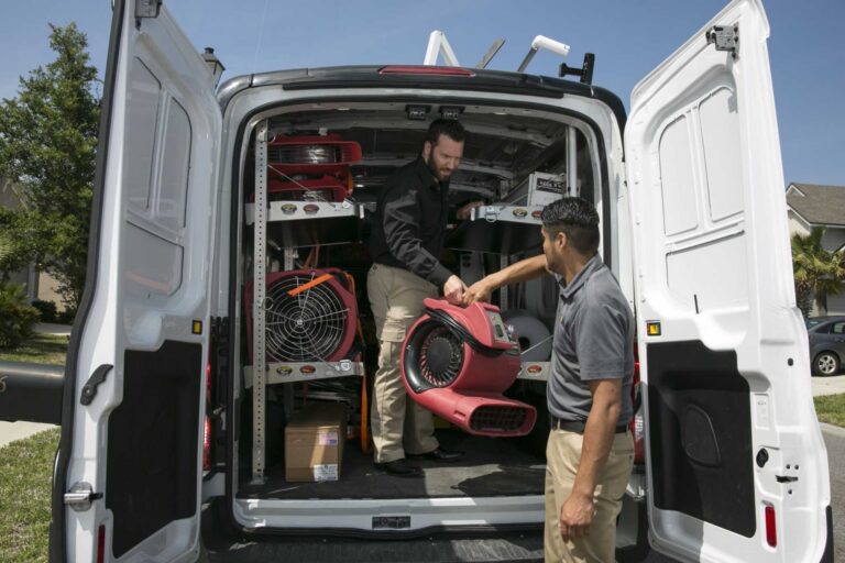 Paul Davis Restoration technicians unloading commercial storm damage drying equipment from service van for emergency property restoration response